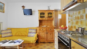 Una cocina funcional con armarios de madera, estufa a gas y protector contra salpicaduras de azulejos.