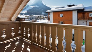 Ein hölzerner Balkon mit Blick auf einen Berg und schneebedeckte Gebäude.