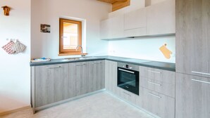 Una cocina moderna con armarios de madera, horno empotrado y ventana con persianas.
