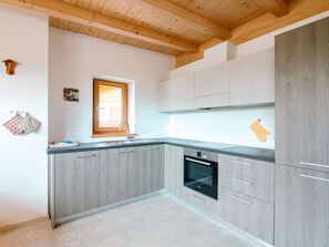 Een koelkast, een oven, een vaatwasser, kookgerei, borden en bestek