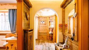 A wooden interior with a narrow hallway leading to a room with a window.