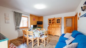 Un espacio habitable compacto con comedor, cocina y un sofá azul.