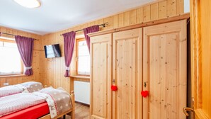 Una habitación de madera con dos camas, un televisor y un armario con pomos rojos.
