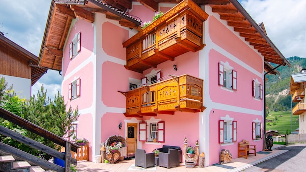Un edificio rosa con balcones de madera y una escalera que lleva a la entrada.