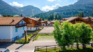 Eine Reihe traditioneller Holzhäuser mit Balkonen, vor einer Berglandschaft und blauem Himmel.