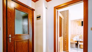 Eine Holztür mit Glasfenster, ein Fliesenboden und Blick in einen Raum mit einer Holzwand und einem Tisch.
