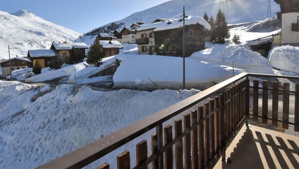 Un pueblo cubierto de nieve con casas tradicionales, una cerca de madera y un cielo despejado.