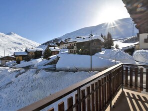 Un village enneigé, avec des maisons traditionnelles, une clôture en bois et un ciel dégagé.