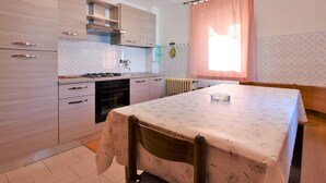 Cocina compacta con comedor, que presenta armarios de madera clara, una estufa a gas y una mesa dispuesta para dos personas.