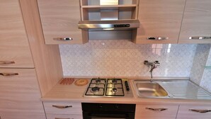 Una cocina moderna con estufa a gas, horno y pileta de acero inoxidable.
