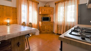 A cozy kitchen with wooden cabinets, a dining table, and a gas stove.
