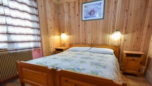 A wooden-paneled room with a double bed, two bedside tables, and a framed picture on the wall.