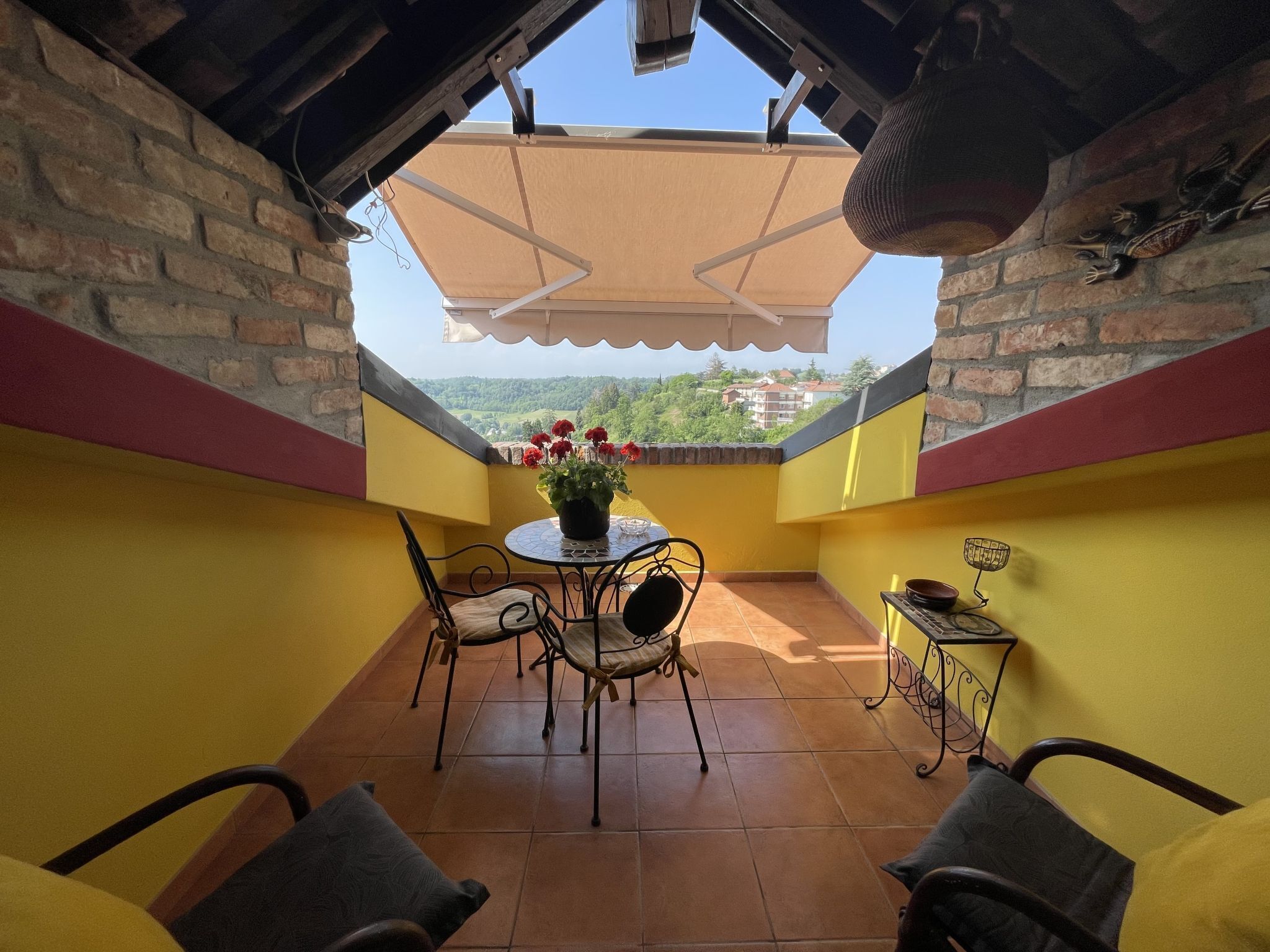 A balcony with a table, chairs, and a potted plant.
