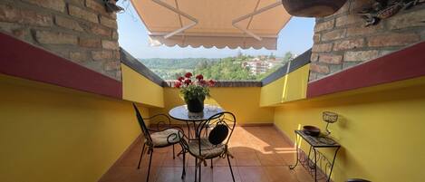 A balcony with a table, chairs, and a potted plant.