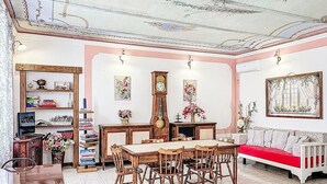 A dining area with a wooden table and chairs, a clock, and a sofa with a red cushion. - Il Cavaliere by Interhome (Asti)