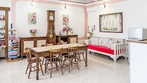 A dining area with a wooden table and chairs, a tall grandfather clock, and a sofa with a red cushion. - Il Cavaliere by Interhome (Asti)
