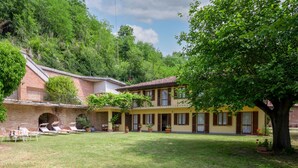 Un bâtiment à deux étages avec une façade en briques, un balcon et un patio couvert doté de sièges extérieurs.