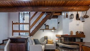 Un interior rústico con vigas de madera a la vista, una chimenea, un banco de piedra y un rincón de estar acogedor.