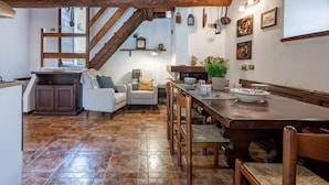 Una cocina rústica con techo de madera, una mesa de comedor y una escalera que lleva a un nivel superior.