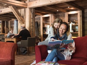 A cozy wooden interior with a red sofa, a wooden table, and a bar area in the background.