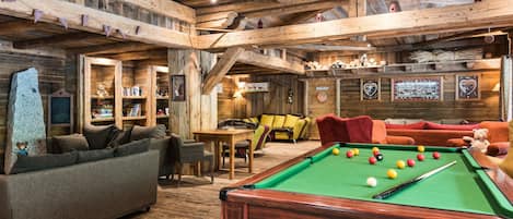 A cozy indoor setting with a pool table, sofas, and a fireplace.