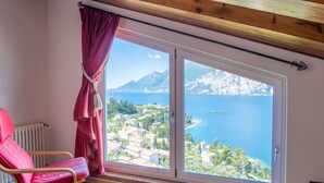A room with a large window offering a view of a coastal town and the sea. - Vacation home Verdin by Interhome (Malcesine)