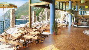 Una habitación soleada con sillones de madera, una cinta de correr y vistas al mar y a las montañas.