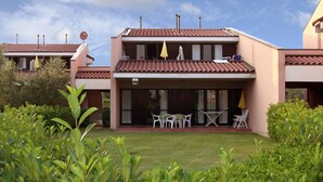 Un bâtiment à deux étages, doté d’un toit plat, d’un balcon et d’un espace extérieur abrité avec des tables et des chaises.