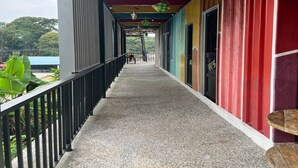 A covered corridor with a metal railing, colorful walls, and a view of greenery outside. - Hotel O Ting Brother Sg Klah Inn (Sungkai)