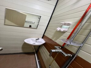 Ett badrum med ett vitt handfat, en spegel och en handtork.