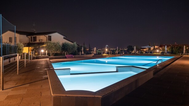 A rectangular swimming pool with a clear blue water surface, surrounded by a tiled deck.