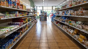 A grocery store aisle with shelves stocked with various products including beverages, snacks, and packaged goods.