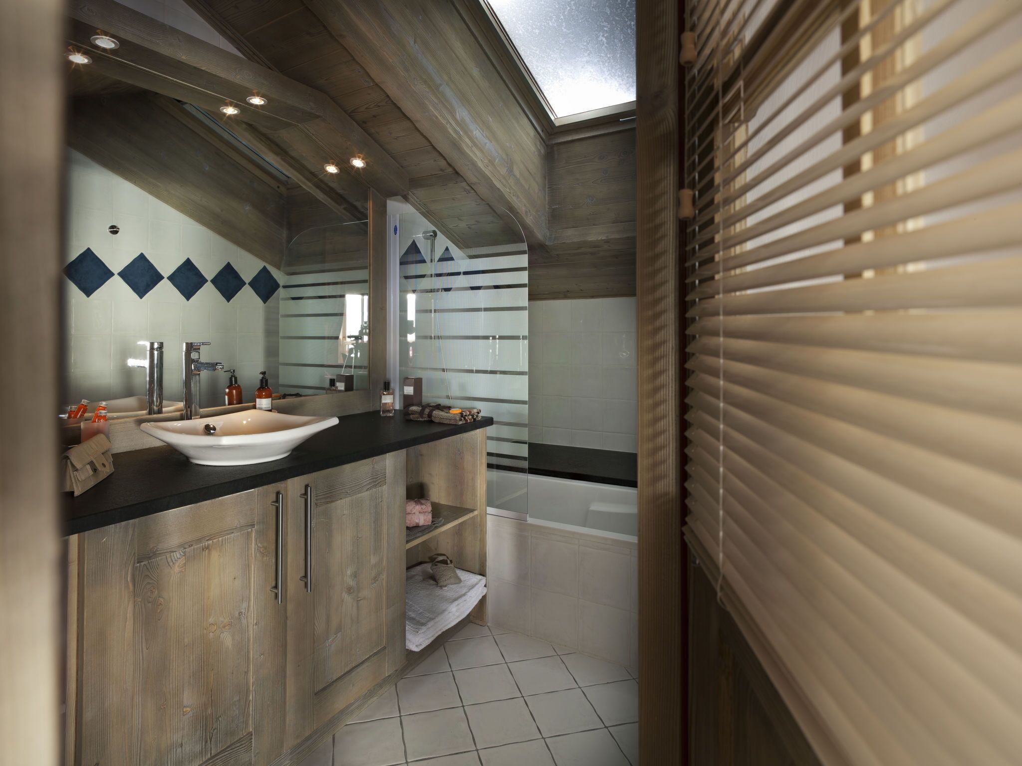 A modern bathroom with a skylight, a freestanding bathtub, and a vanity with a large mirror.