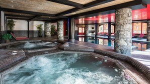 A spa area with a hot tub, stone pillars, and a view of the outside. - Le Télémark 5* by Interhome (Tignes)
