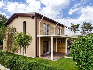 Ein modernes, zweistöckiges Haus mit Balkon, Holztür und gepflegtem Garten.