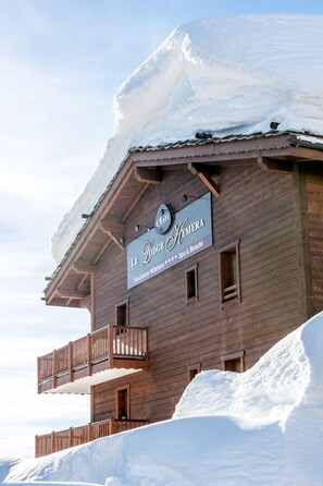 En træbygning med skilt for "Le Lodge Hemera", der angiver at det er et hotel med spa og skønhedsbehandlinger.