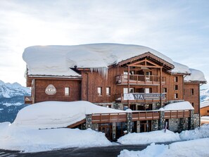 A wooden building with a spa sign, surrounded by snow.