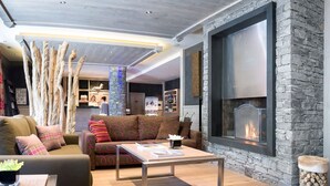 Una sala de estar moderna con chimenea de piedra, piso de madera y un sofá con cojines estampados.