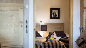 Una habitación acogedora con una cama, una mesita de noche con un frutero, una lámpara y una puerta de madera.
