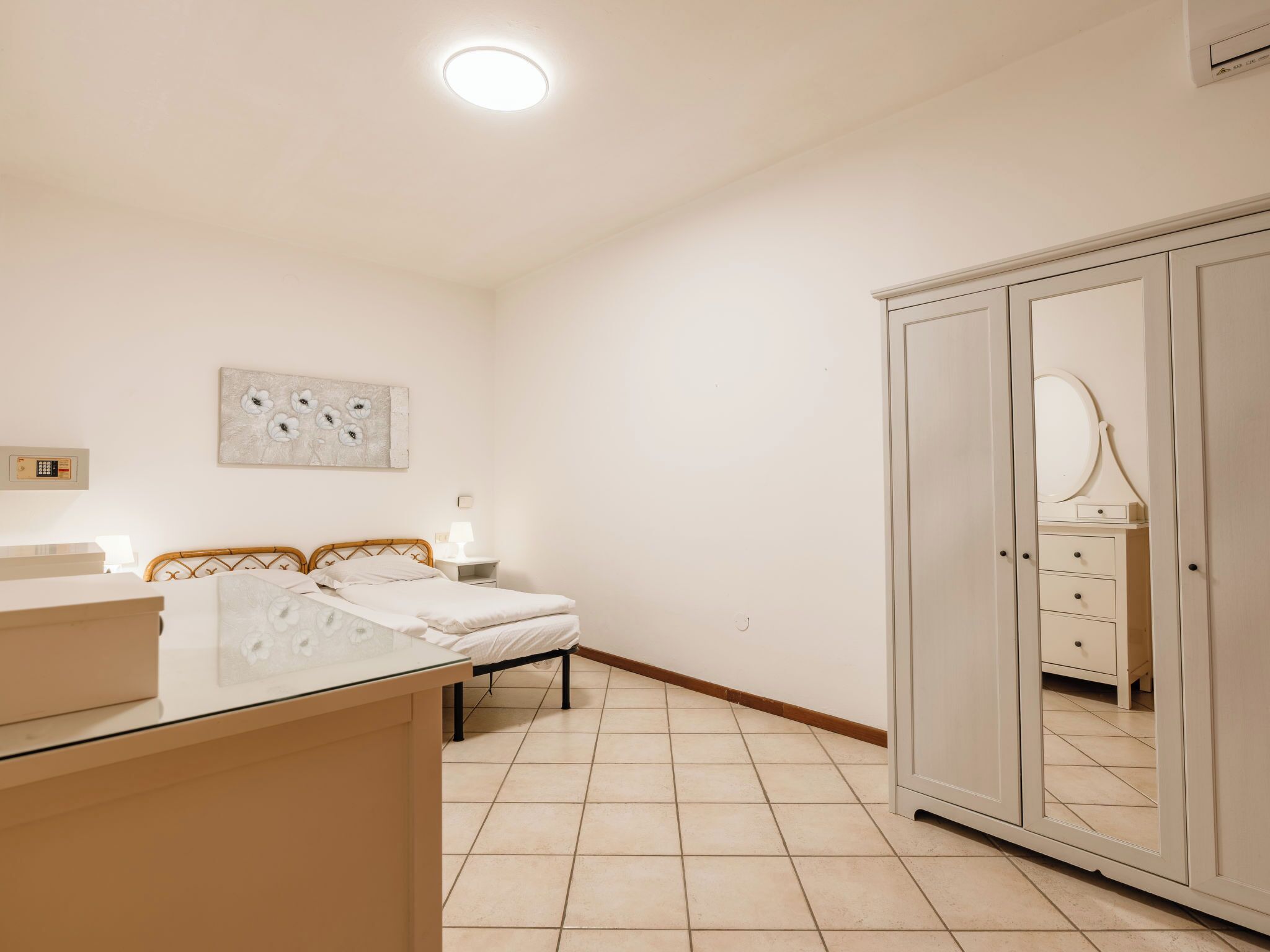 A bedroom with a bed, bedside table, lamp, wardrobe, and a ceiling light.