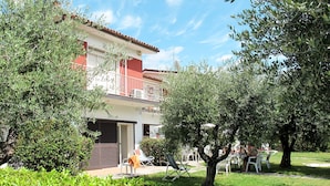 A two-story building with a balcony, surrounded by greenery and trees. - La Villa 2 by Interhome (Manerba)