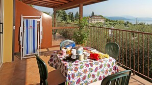 Un balcone con un tavolo apparecchiato per mangiare, una sedia e vista su un edificio in lontananza.