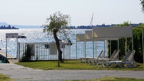Vista de un lago con un pabellón, sillas de descanso y un muelle.