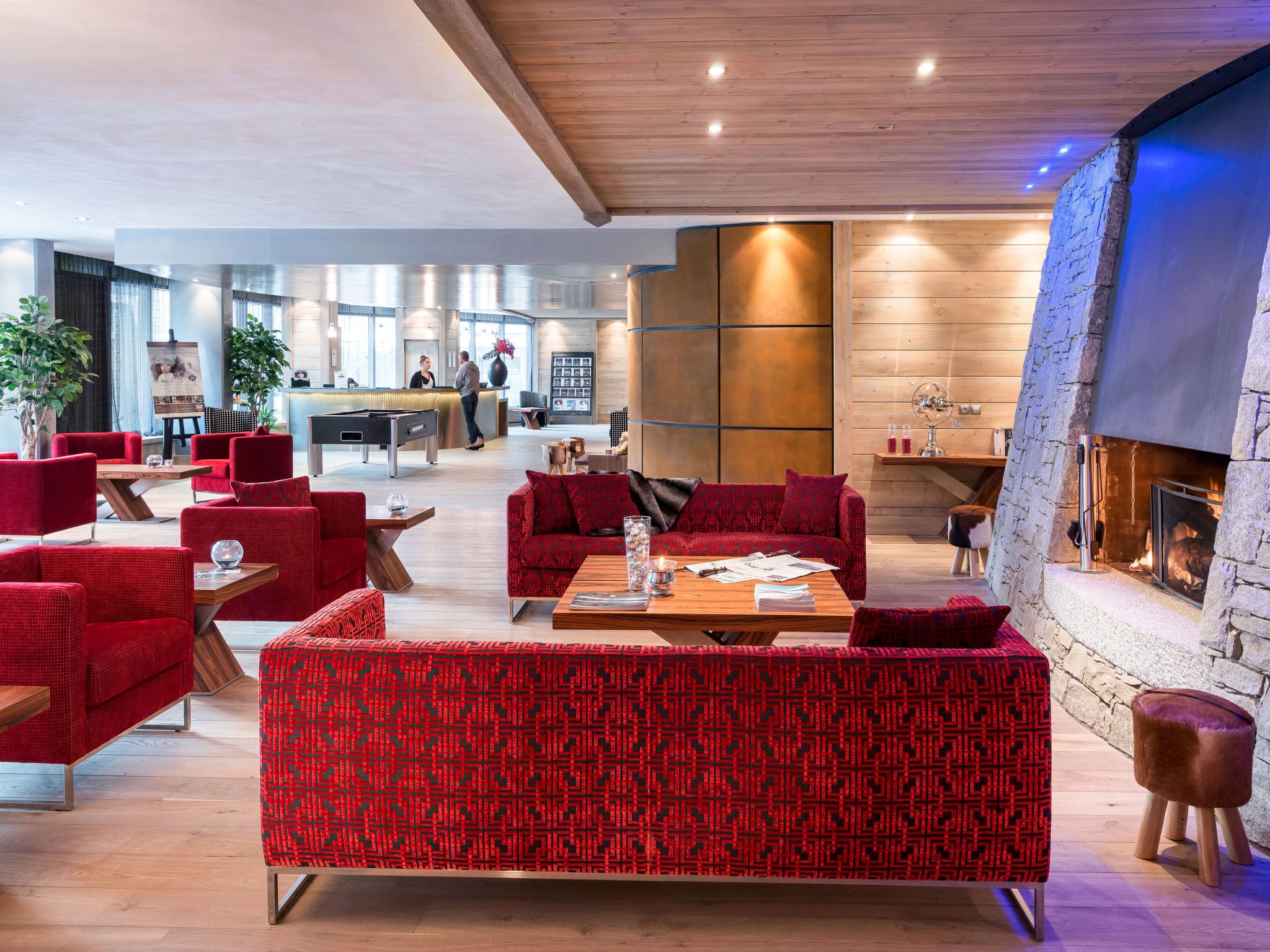 Un área de lounge moderna con sofás estampados en rojo, una mesa de billar y una chimenea.