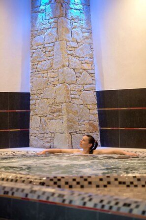 A person relaxing in a hot tub with a stone wall behind them. - CGH Résidence & Spa Le Centaure 5* by Interhome (Flaine)