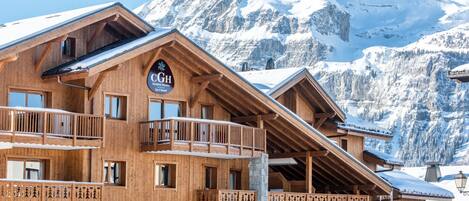 A wooden chalet with balconies, a sign reading 'CGH Residence Hôtellerie Spa & Beauté', and a mountain backdrop.