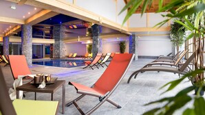 Un espace aménagé au bord de la piscine, avec des chaises longues, une table où sont posées des boissons et la piscine elle-même.