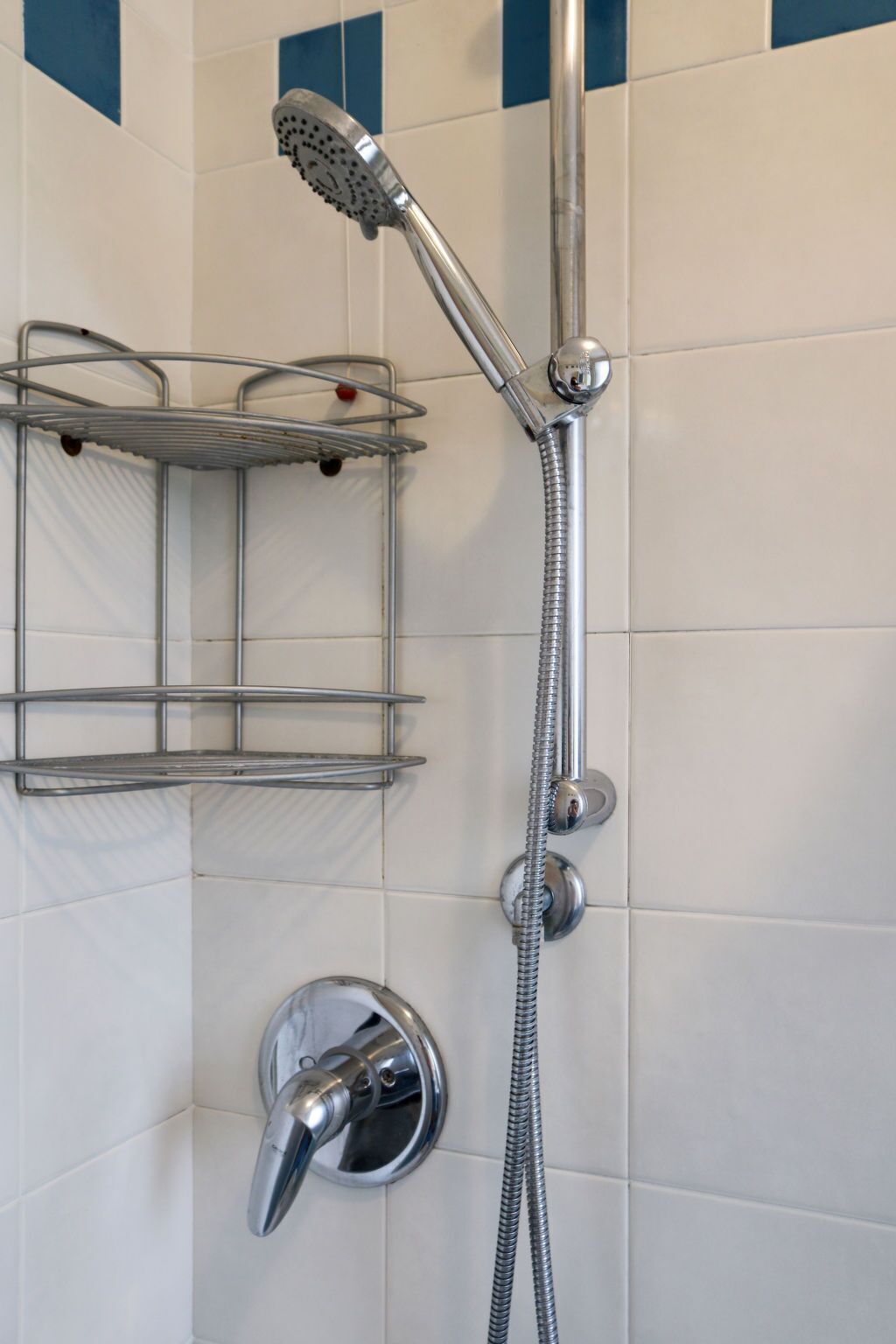 Een douche met een handdouche en een wandmengkraan.