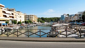 A marina with boats docked, a wooden walkway, and buildings in the background.