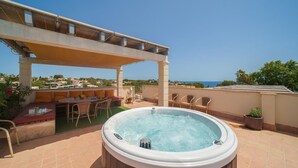 A rooftop terrace with a hot tub, outdoor seating, and a pergola.